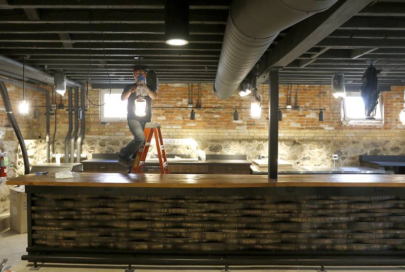 A worker uncovers a light above a bar inside the newly remodeled Old Courthouse Center in Woodstock on Thursday, July 13, 2023, during a tour of the building.