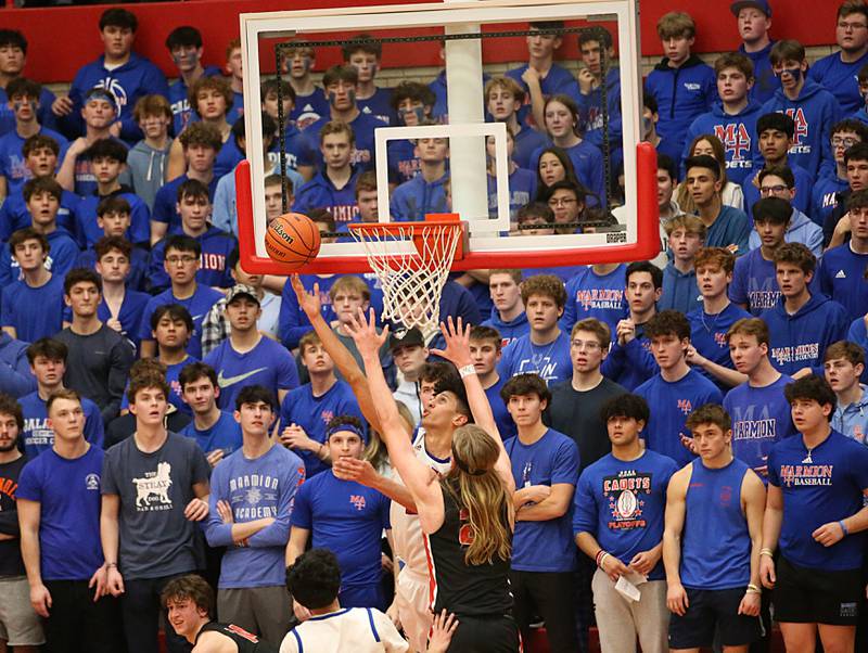Marmion's Travon Roots (center) does a reverse layup as Metamora's Ethan Kizer defends during the Class 3A Super-Sectional on Monday, March 6, 2023 at Ottawa High School.