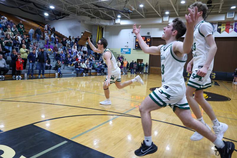Bishop McNamara's Callaghan O'Connor carries the IHSA Class 2A Herscher Regional championship plaque toward the student section alongside teammates Teddy Fogel, near, and Richard Darr as they celebrate the Fightin' Irish's 66-52 victory over El Paso-Gridley on Friday, Feb. 27, 2026.