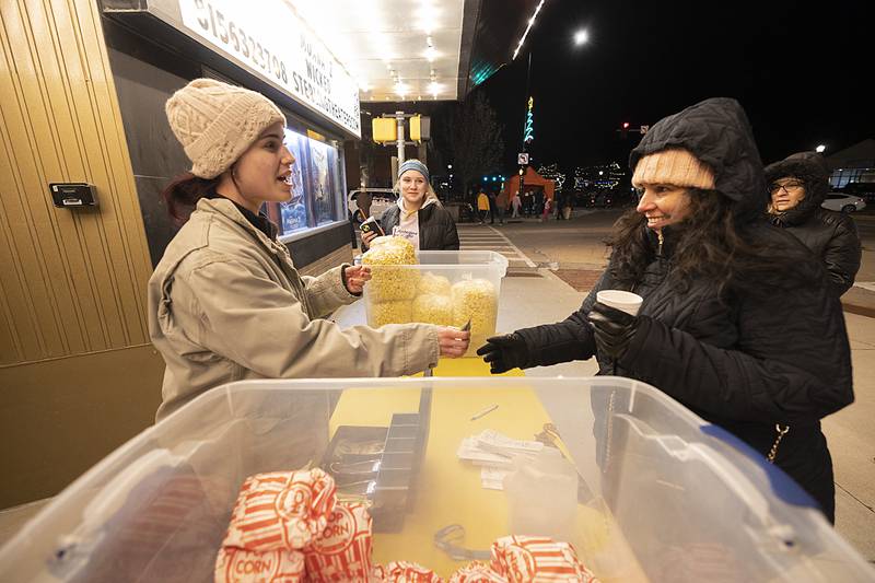 Caitlin Williamson (left) sells Tracy Perea some hot and fresh popcorn Friday, Dec. 6, 2024, outside of the Sterling theater during Sterling’s Sights and Sounds Christmas event.
