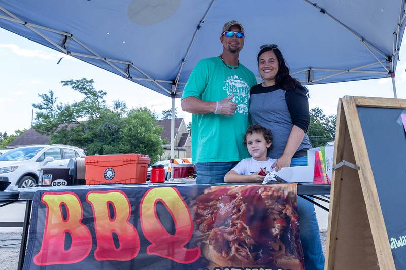 (from left) Richie Scott, his son Richie Jr. and Wife Katie Scott stand behind table for Reid's Smokehouse on Monday, Aug 25, 2025 on Illinois Avenue in Mendota.