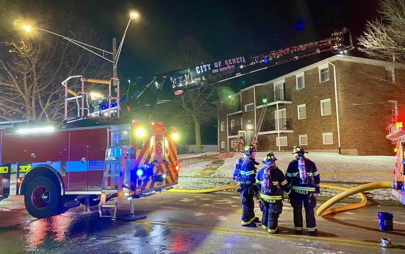 Three DeKalb firefighters stand ready to aid crews responding to an apartment fire next to a Geneva Fire Department ladder engine on Sunday, Dec. 22, 2024, at 1024 W. Hillcrest Drive in DeKalb. The blaze, just before Christmas, is expected to impact multiple residents in the three-building complex.
