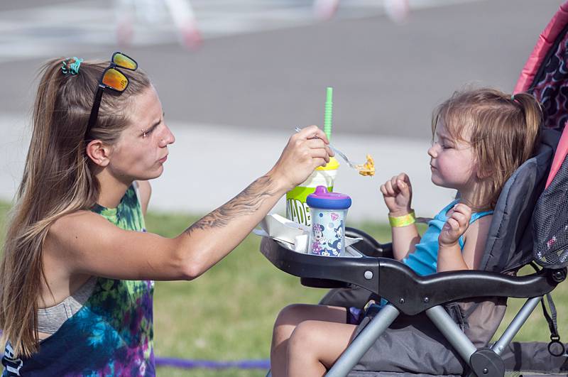 Hallie Diveley shares her carnival food with daughter Alyza Harris, 2, during the opening day of Dixon’s Petunia Fest carnival on Thursday, June 30, 2022.