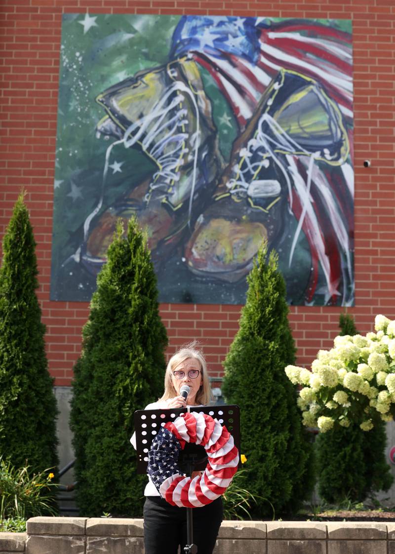 Cindy Hupke, from the DeKalb American Legion Auxiliary, gives information on the veteran suicide problem and promotes the Be The One Suicide Walk Thursday, Aug. 22, 2024, during the DeKalb Veterans Memorial Mural dedication in Van Buer Plaza in downtown DeKalb.