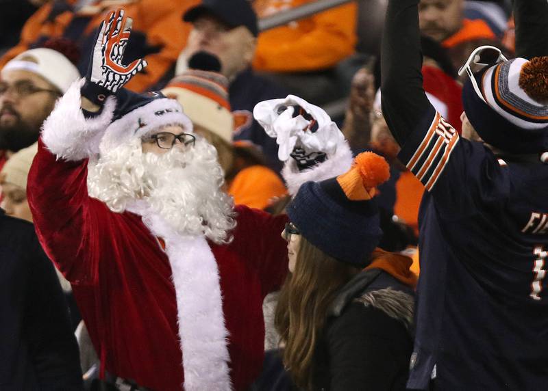 Santa Claus high-fives a fellow Chicago Bears fan late in the fourth quarter of their game against the Arizona Cardinals Sunday, Dec. 24, 2023, at Soldier Field in Chicago.