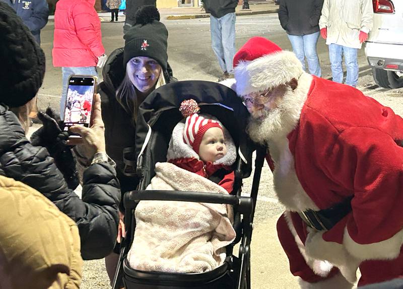 Madelyn Harrison, 1, of Dixon, checks out Santa Claus with her mom Elizabeth, as Laurie Chilton takes a photo during Mt. Morris' Christmas in the Village on Saturday, Dec. 7, 2024.