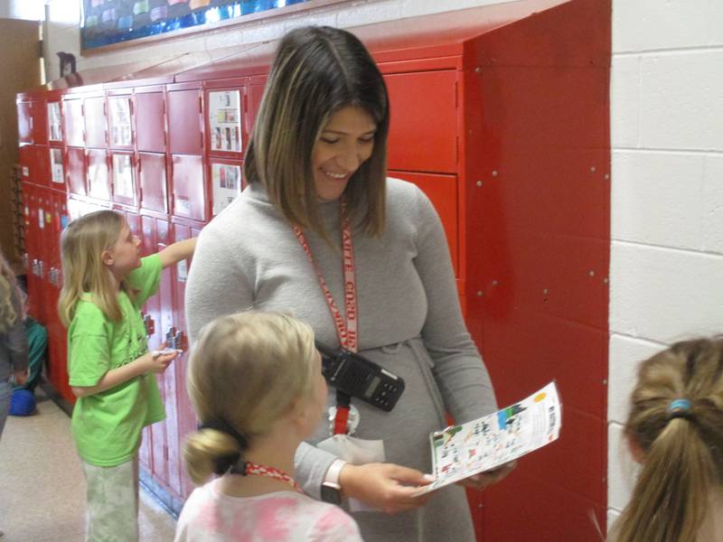 Yorkville Grade School social worker Adriana Resendiz smiles as she reviews a student's work during a "gratitude walk" through the school hallways.