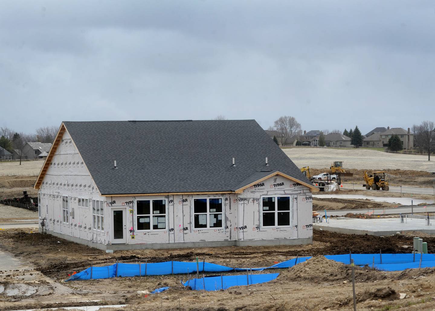 A construction worker builds a home Thursday, April 7, 2022, in the new Trails of Woods Creek, a planned 279-unit subdivision in the Huntley School District.