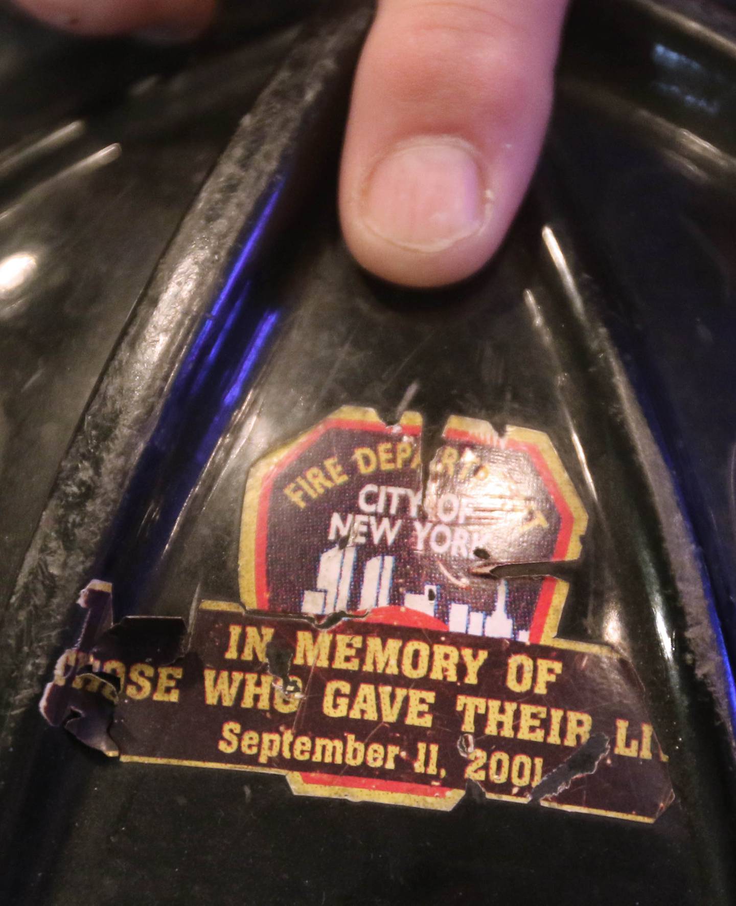 DeKalb firefighter/paramedic Pat Eriksen, points out the 9/11 sticker on one of his helmets Monday, Aug. 30, 2021, in his Sugar Grove home, as he talks about his cousin John Joseph Florio, a New York City firefighter from Engine Company 214 out of Brooklyn, who was killed while responding to the Twin Towers during the Sept. 11, 2001 terrorist attacks. This year marks the 20th anniversary of the tragedy.