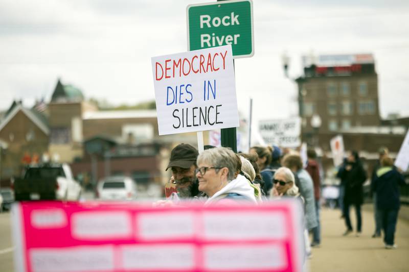 Protestors line the edges of the Galena Avenue bridge in Dixon Saturday, April 19, 2025, voicing their opinion of President Trump and their feelings the administration is not following a Democracy based government.