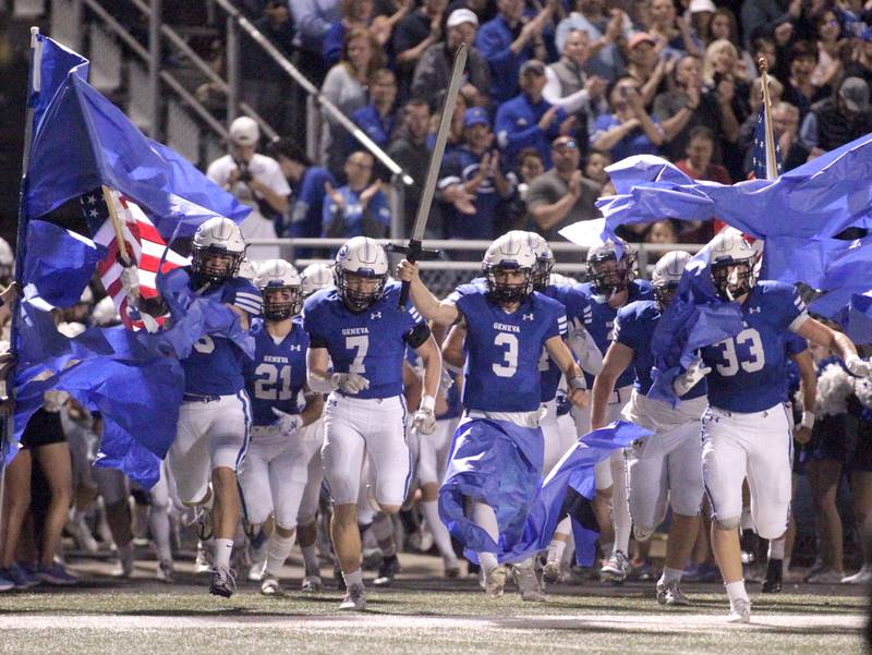 Geneva quarterback Nate Stempowski (center) carries the sword as he leads the team onto the field ahead of their game against Batavia in Geneva on Friday, Sept. 29, 2023.