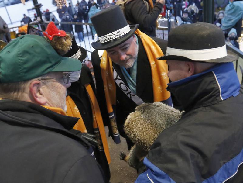 Woodstock Mayor Mike Turner tries to determine if Woodstock Willie saw or did not see his shadow as Willie is held by handler Mark Szafarn Wednesday, Feb, 2, 2022, during the annual Groundhog Day Prognostication on the Woodstock Square. This is the 30th anniversary of when the movie “Groundhogs Day” was filmed in Woodstock.