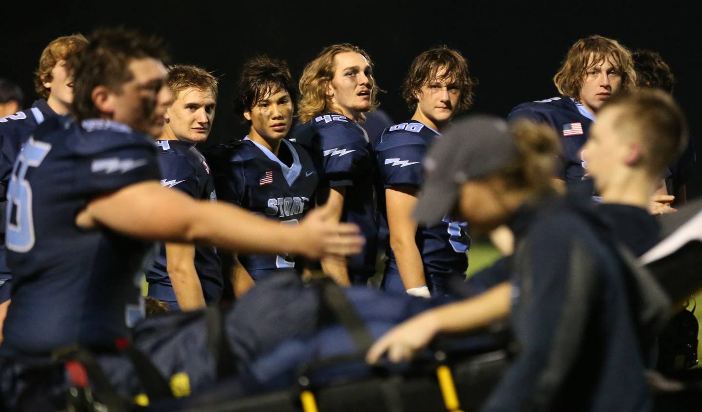 Members of the Bureau Valley football team watch teammate Blake Helms get carted off of the field after breaking his leg against Mendota on Friday, Sept. 22, 2023 at Bureau Valley High School.