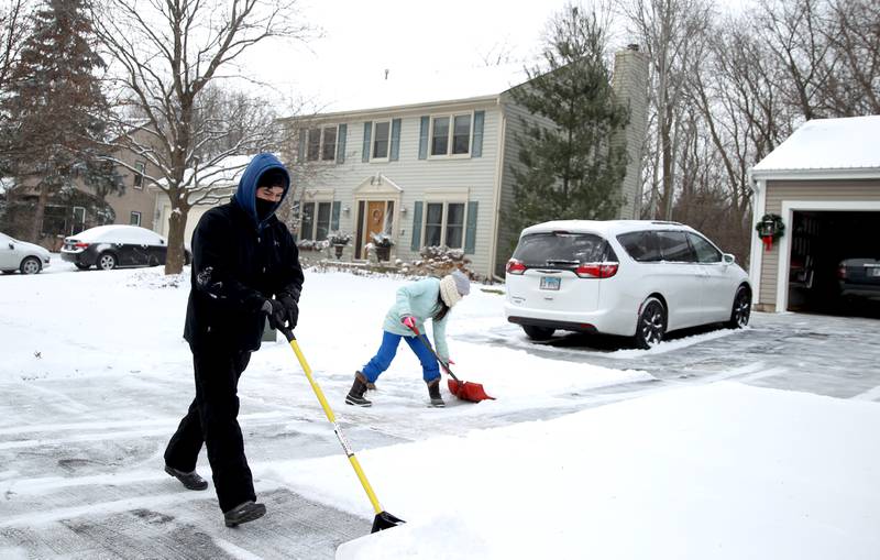 Luis Villa and his daughter, Alex, 13, shovel the driveway of their Batavia home as the temperatures dip below zero on Friday, Dec. 23, 2022.