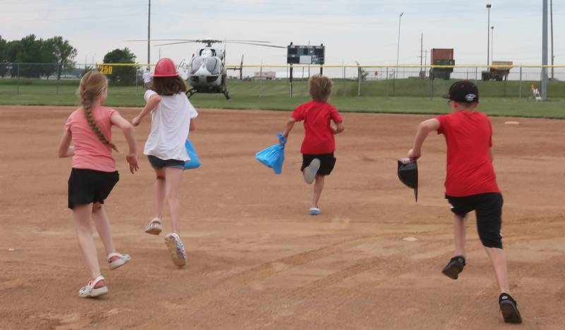 Kids run onto the softball field to check out OSF Lifeflight helicopter during the Illinois Valley Pistol Shrimp First Responder Night on Tuesday, June 17, 2025 at Schweickert Stadium in Peru.