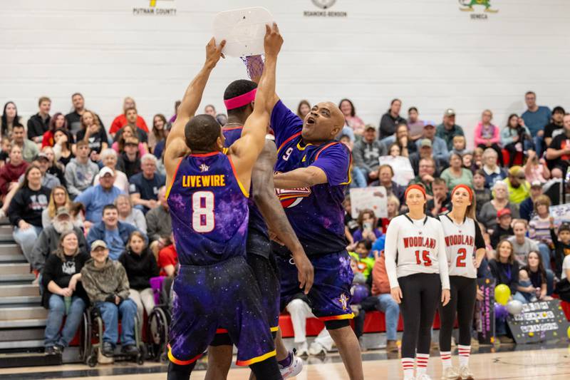 Arnold “A-Train” Bernard (9) of the Harlem Wizards “dunks” on teammate Kamil “Dragon” Brown (77) whilst Devon “Livewire” Curry (8) holds mini basketball hoop on Wednesday, April 16, 2025 at Woodland High School in Streator.