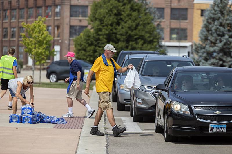 Volunteer Bob Sondgeroth delivers meals of pork chops and sweet corn to a car Monday, July 24, 2023 for the annual Rotary Corn Boil and BBQ Pork Chop sale. The Sterling Noon and Rock Falls Rotary Clubs combined forces three years ago for the annual summer lunch special.