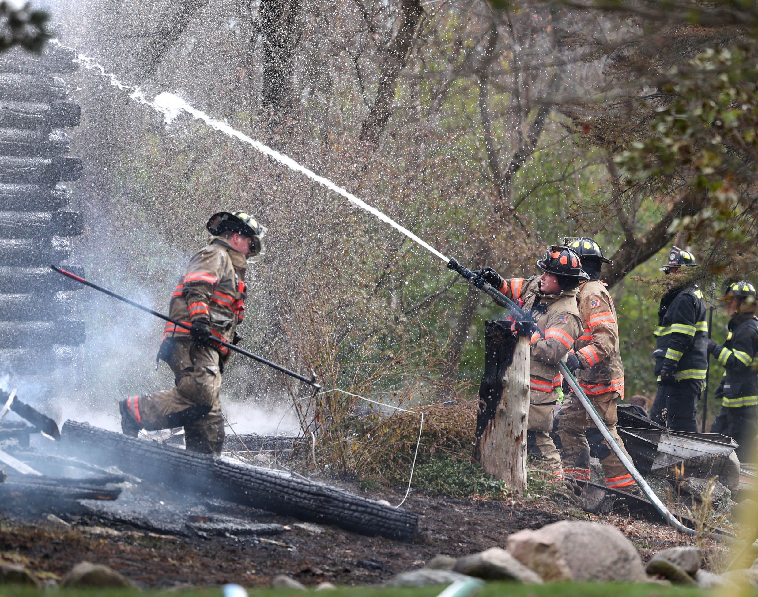 Firefighters spray water on a smoldering house that was destroyed by fire Thursday, Nov. 13, 2025, near Shabbona Grove Road in Shabbona. Several local departments responded to the general alarm structure fire.