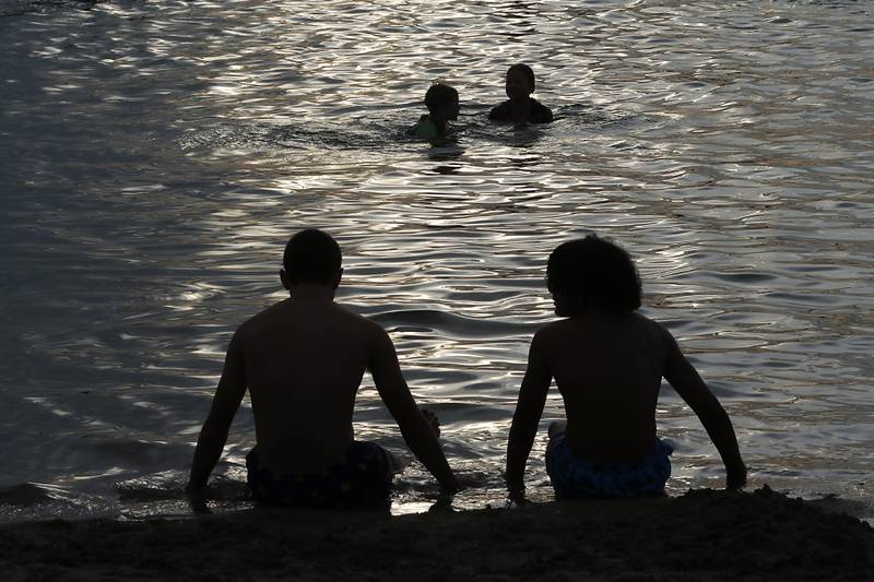 People enjoy the waters of Crystal Lake during the Crystal Lake Park District's Concert in the Park on Tuesday, June 17, 2025, at Main Beach in Crystal Lake. The concert was part of the park district's weekly Tuesday night summer concert series.