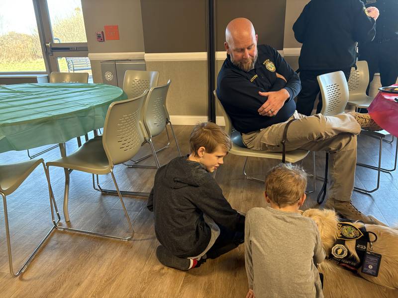Officer Jason Sterwerf watches as children pet Oakley the Therapy Dog Dec. 8, 2024 during the Shop with a Cop event in McHenry.