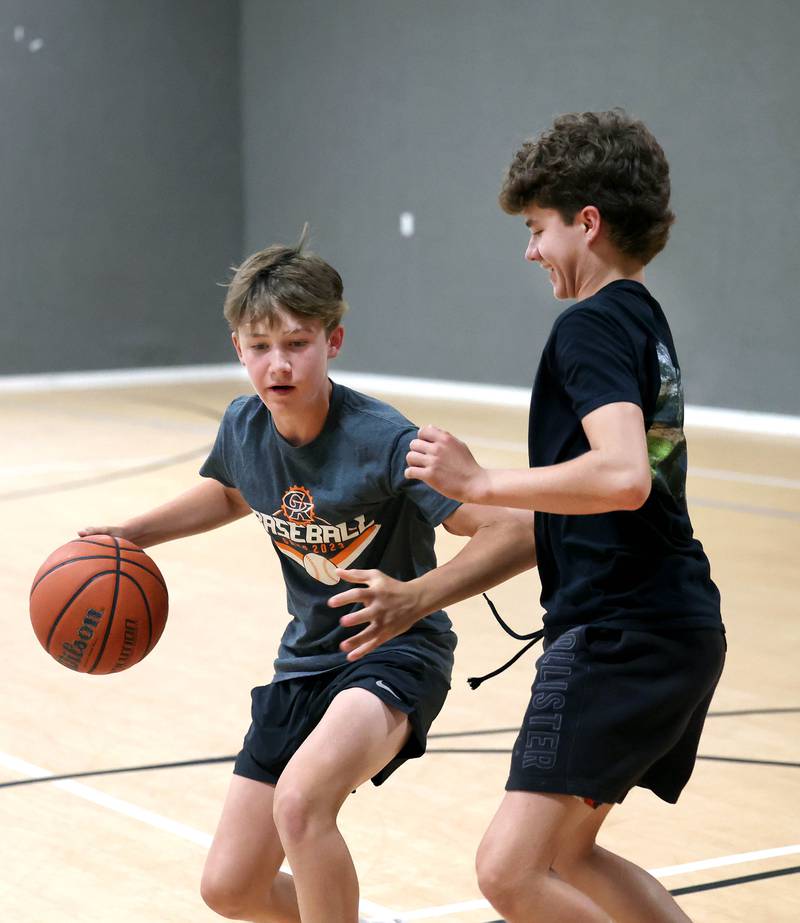 Caleb Krueger, (left) 13, is guarded by his brother Cole, 15, Wednesday, Aug. 28, 2024, as they play basketball at their house in Genoa. The pair recently earned Guinness World Record record for the most basketball passes in a minute for a pair under 16 and are planning an attempt at breaking the world record for the most three pointers in a minute by a duo.