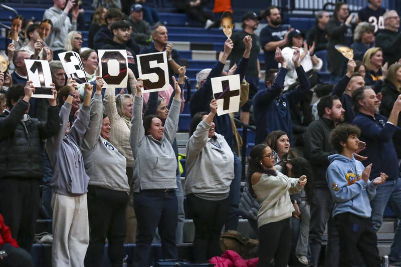 Fans in the stands hold up a sign celebrating Aubrey Lamberti's all time girls scoring record basket, during their basketball game between Minooka at Oswego East Friday, Jan 16, 2026 in Oswego.