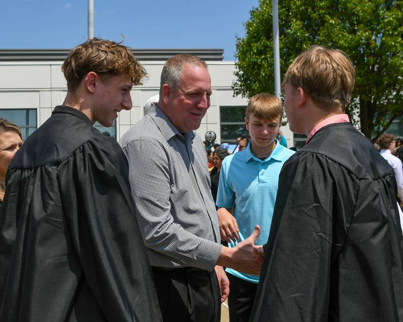 DeKalb’s varsity boys head coach Mike Reynolds congratulates some of DeKalb High School's Class of 2025 graduates on Saturday, May 24, 2025, after the Class of 2025 Commencement ceremony held at the NIU Convocation Center in DeKalb.