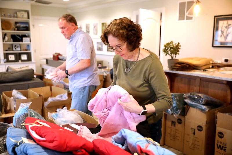 Volunteers Karin and John Sweeney of Geneva sort children’s winter coats to be donated to the Salvation Army, Lazarus House and area schools.