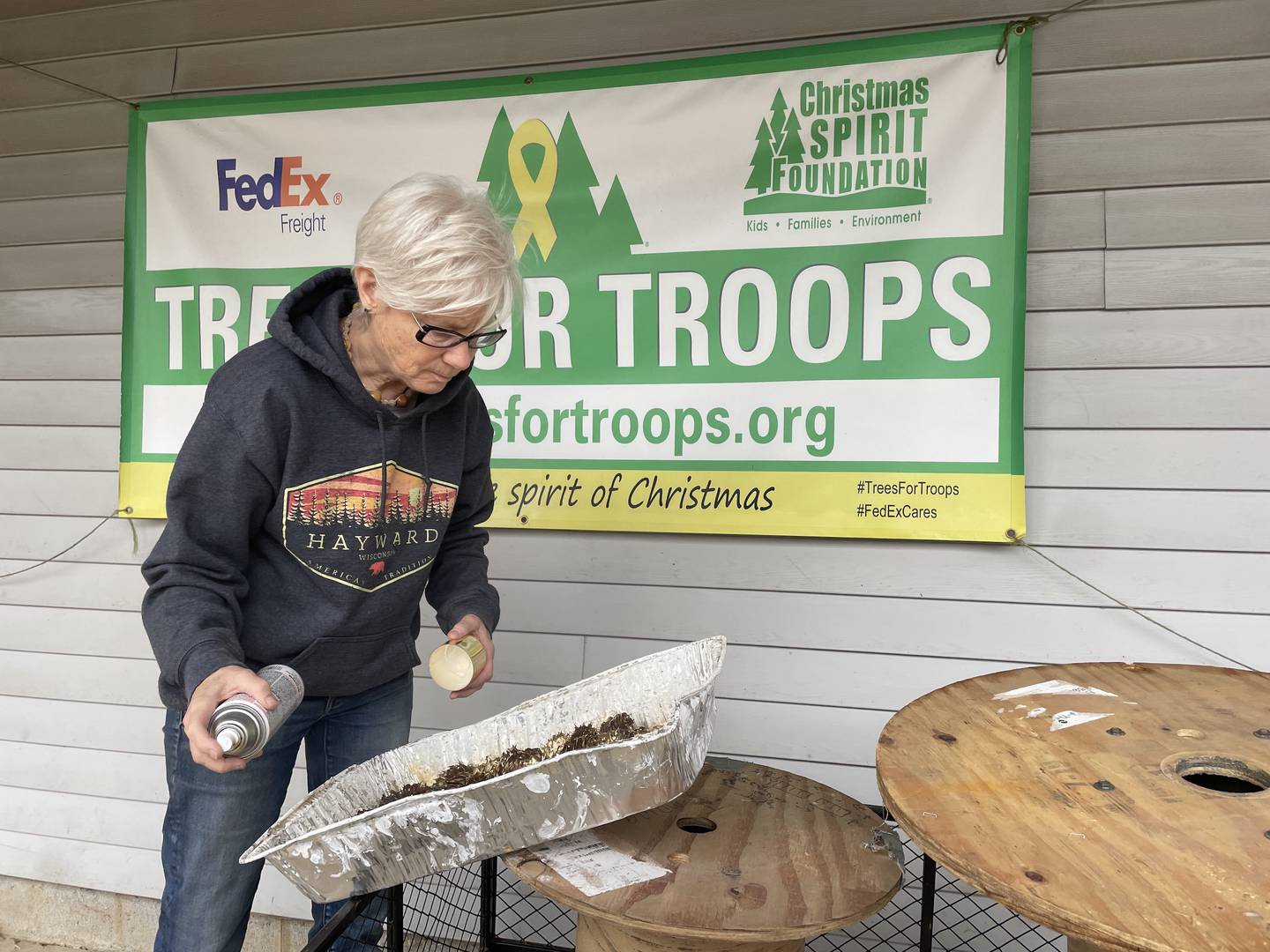 Lisa Bauman of Spring Grove inspects her handiwork after glazing pinecones with gold paint. The cones add splash to centerpieces and mantel swag hand-crafted on-site at the Richardson Christmas Tree Farm.