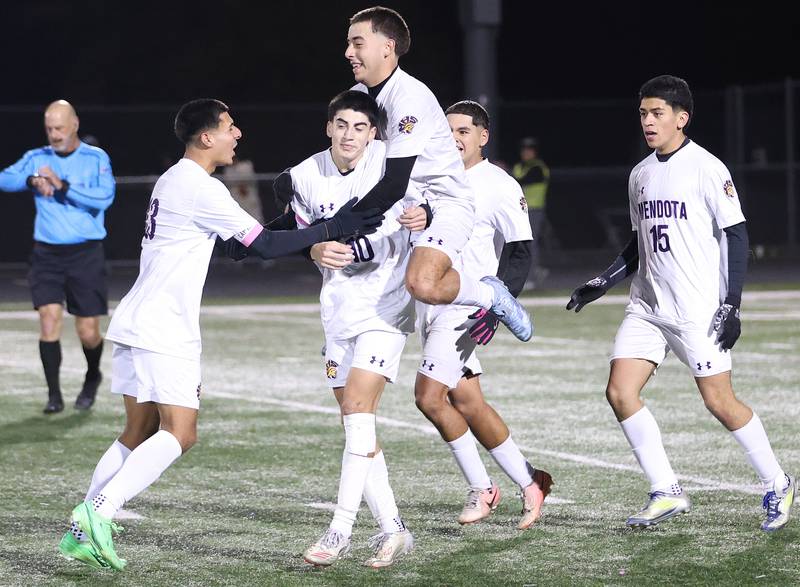 Mendota's Cesar Casas leaps on the back of teammate Johan Cortez while other players join in the celebration after defeating Quincy Notre Dame during the Class 1A Supersectional game on Monday, Nov. 3, 2025 at Mendota High School.