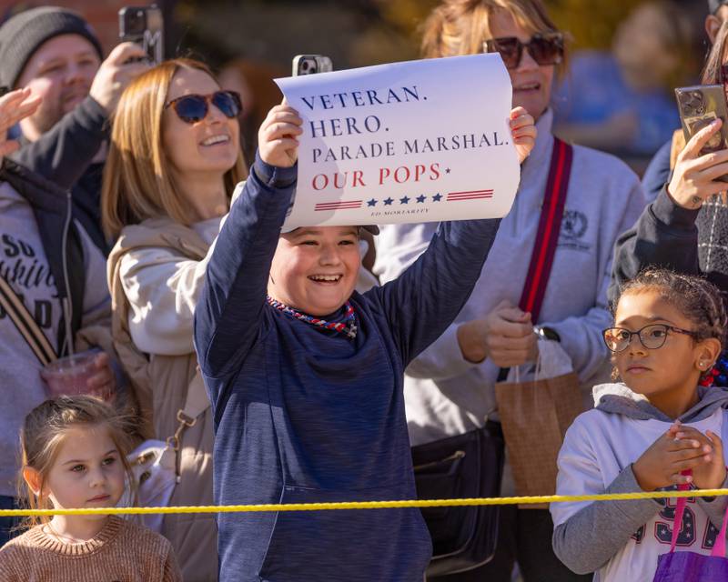 Parade Marshall Ed Moriarity's grandson Jax Smith holds up a sign to celebrate his Grandpa as he goes by during the Utica Veterans Parade and Airshow on November 2, 2025 in Utica.
