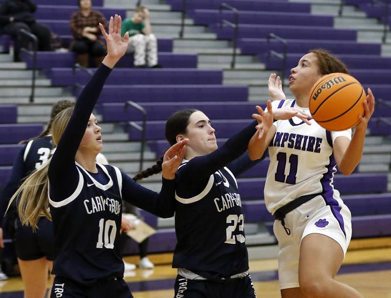 Hampshire's Mikala Amegasse (right) drives to the basket against Cary-Grove's Alivia Nielsen (left) and Avery Hoffman (center) during a Fox Valley Conference girls basketball game on Monday, Dec. 9, 2024, at Hampshire High School.