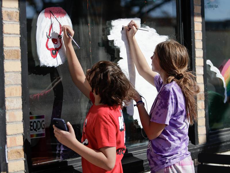 Owen,12, and Eva, 15, Henrikson of Downers Grove paint the windows of Starbucks in Downers Grove, Ill. on Saturday, October 22, 2022.