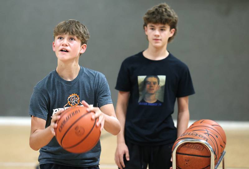 Caleb Krueger, (left) 13, and his brother Cole, 15, practice their three point shots Wednesday, Aug. 28, 2024, at their house in Genoa as they prepare for an attempt to break the world record for three pointers in a minute by a duo. The brothers already own a Guinness Book World Record for the most basketball passes in a minute for a pair under 16.