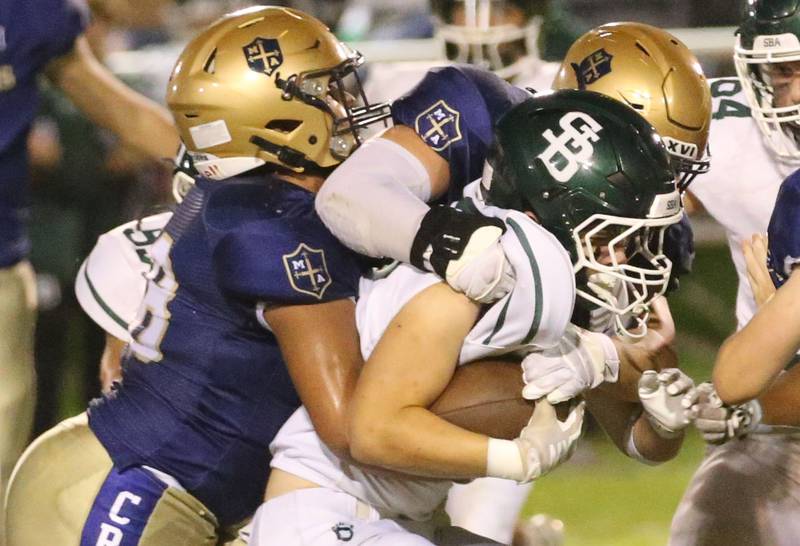 St. Bede's Brennen Hirst is brought down by Marquette's Alex Schafer and Marcus Baker on Friday, Sept. 26, 2025 at Gould Stadium in Ottawa.
