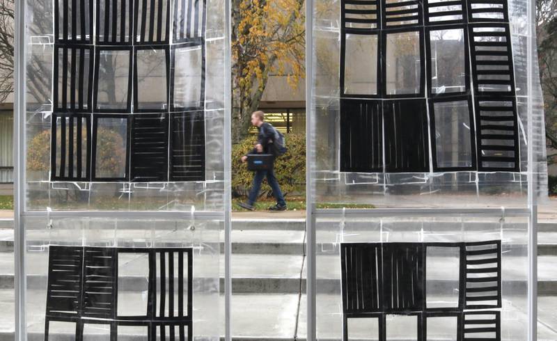 A student walks by the piece “The Day of the Triffids, 1963” by Rebecca Griffith Wednesday, Nov. 8, 2023, outside the Northern Illinois University School of Art and Design, Visual Arts Building. The piece is part of the Terrain Biennial 2023, a countrywide exhibit where artists display their work outside of homes and building around town.