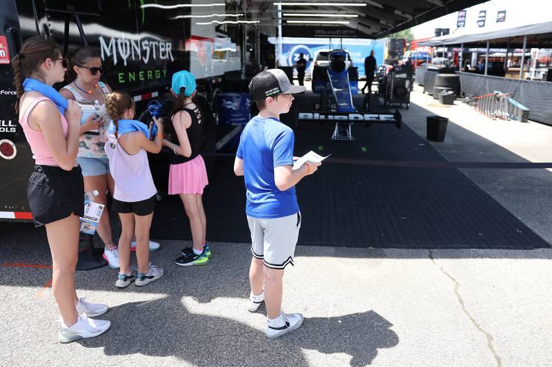 Cory Loyd, center, from Pingeree Grove, IL, hangs out by Brittney Force’s car at the NHRA’s Gerber Collision and Glass Route 66 Nationals at Route 66 Raceway on Sunday, May 19, 2024 in Joliet.