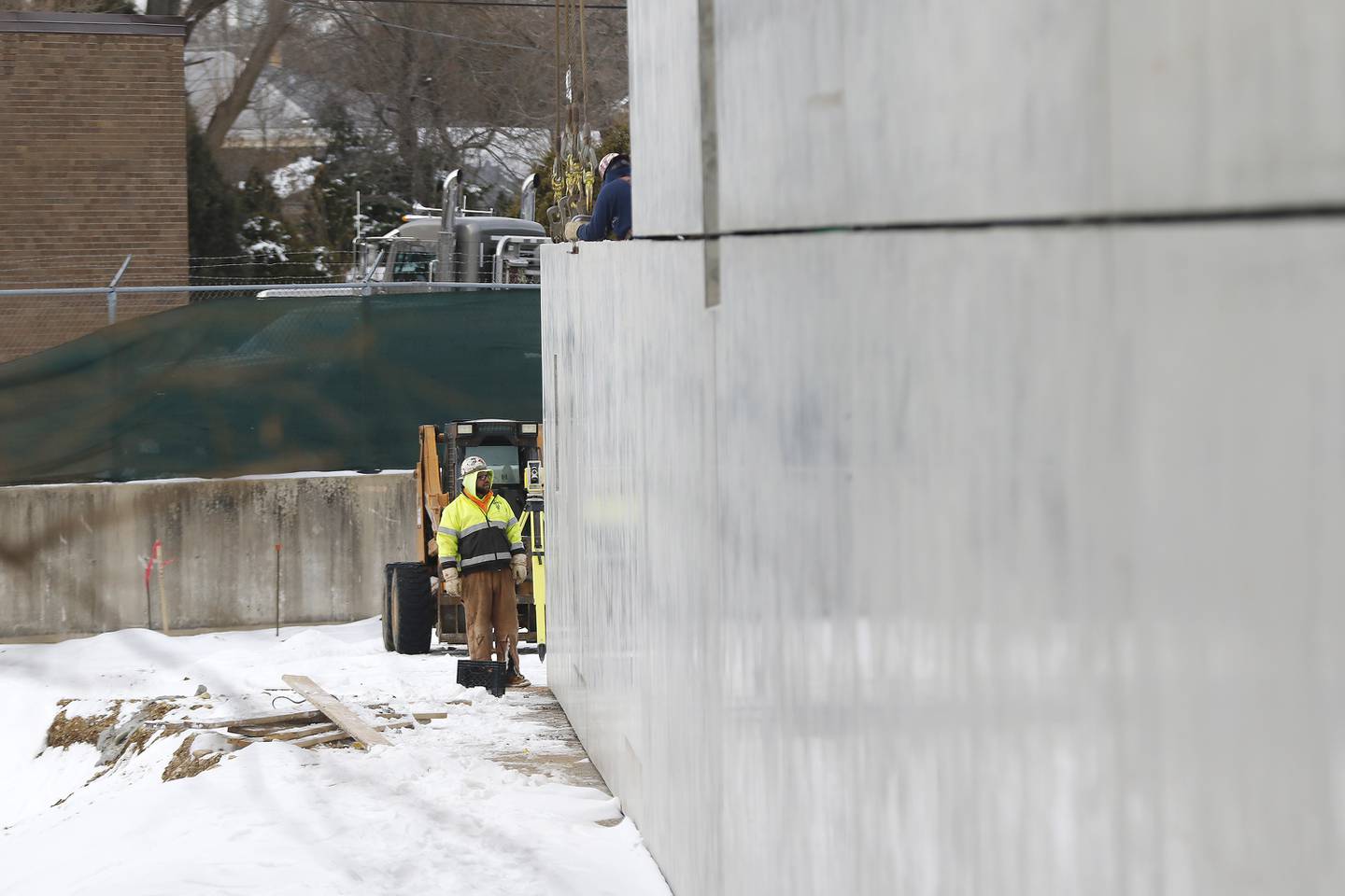Construction workers are seen Tuesday, Jan. 4, 2022, placing walls on a new apartment building's parking structure at the intersection of Algonquin Road and Northwest Highway in Fox River Grove.