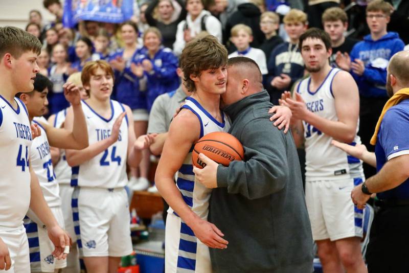 Princeton's Teegan Davis receives a hug and game ball from coach Jason Smith after he scored his 1,000th career point Friday night at Prouty Gym.