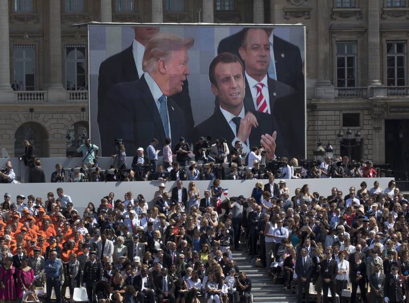 FILE - President Donald Trump, pictured on screen from left, French President Emmanuel Macron and White House Chief of Staff Reince Priebus watch a Bastille Day parade on the Champs Elysees avenue in Paris, July 14, 2017. (AP Photo/Carolyn Kaster, File)