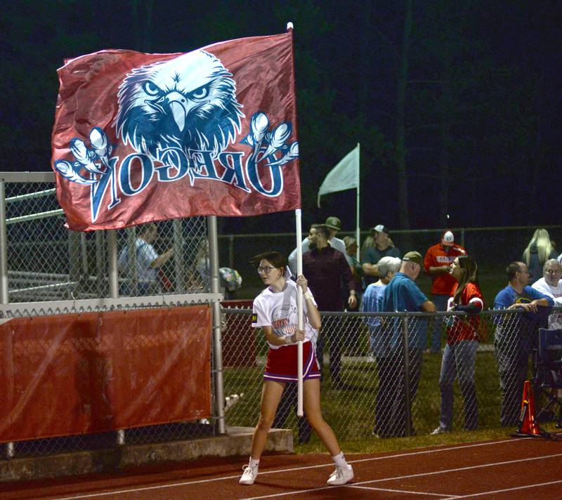 An Oregon cheerleader runs with an Oregon flag during the varsity football game against Genoa-Kingston on Friday, Sept. 13, 2024 at Landers-Loomis Field in Oregon.
