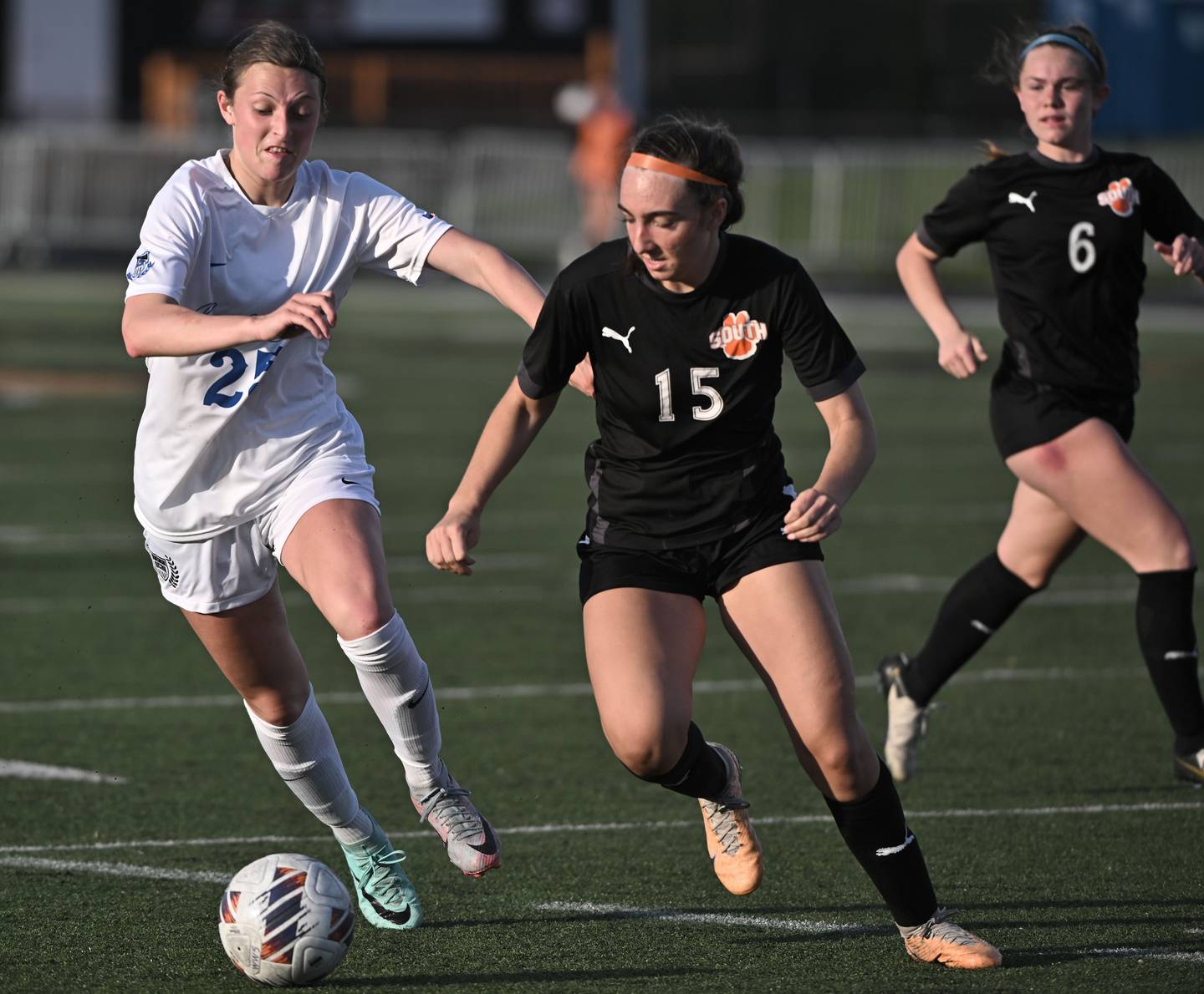 St. Charles North’s Kaitlin Glenn and Wheaton Warrenville South’s Kayla Waterman, right, chase the ball in the final second of a girls soccer game in Wheaton on Tuesday, April 16, 2024.