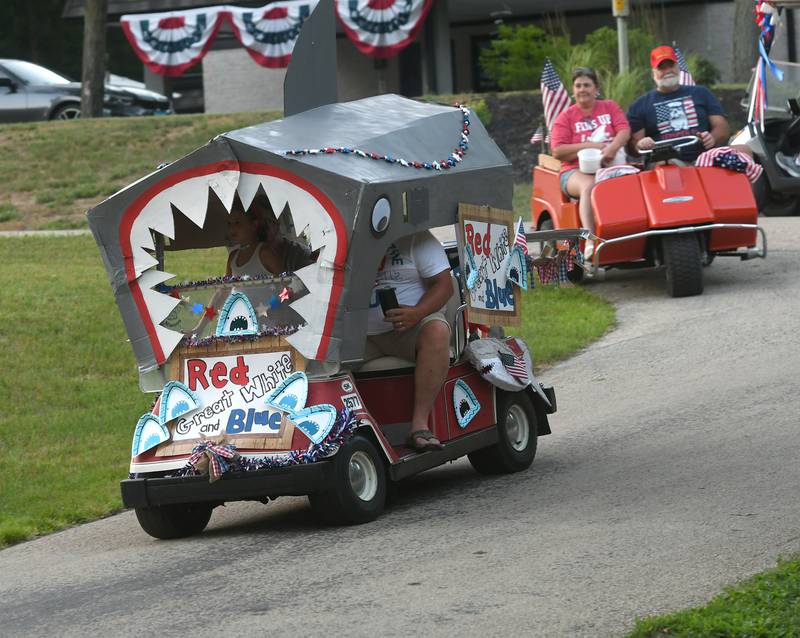Mark and Linda Downey's decorated golf cart, "The Red Great White and Blue" heads down a street during the 2022 Grand Detour Golf Cart Parade followed by Mike and Sherry Shaulis' vintage 1969 vintage Harley Davidson golf cart. This year's parade is Saturday.