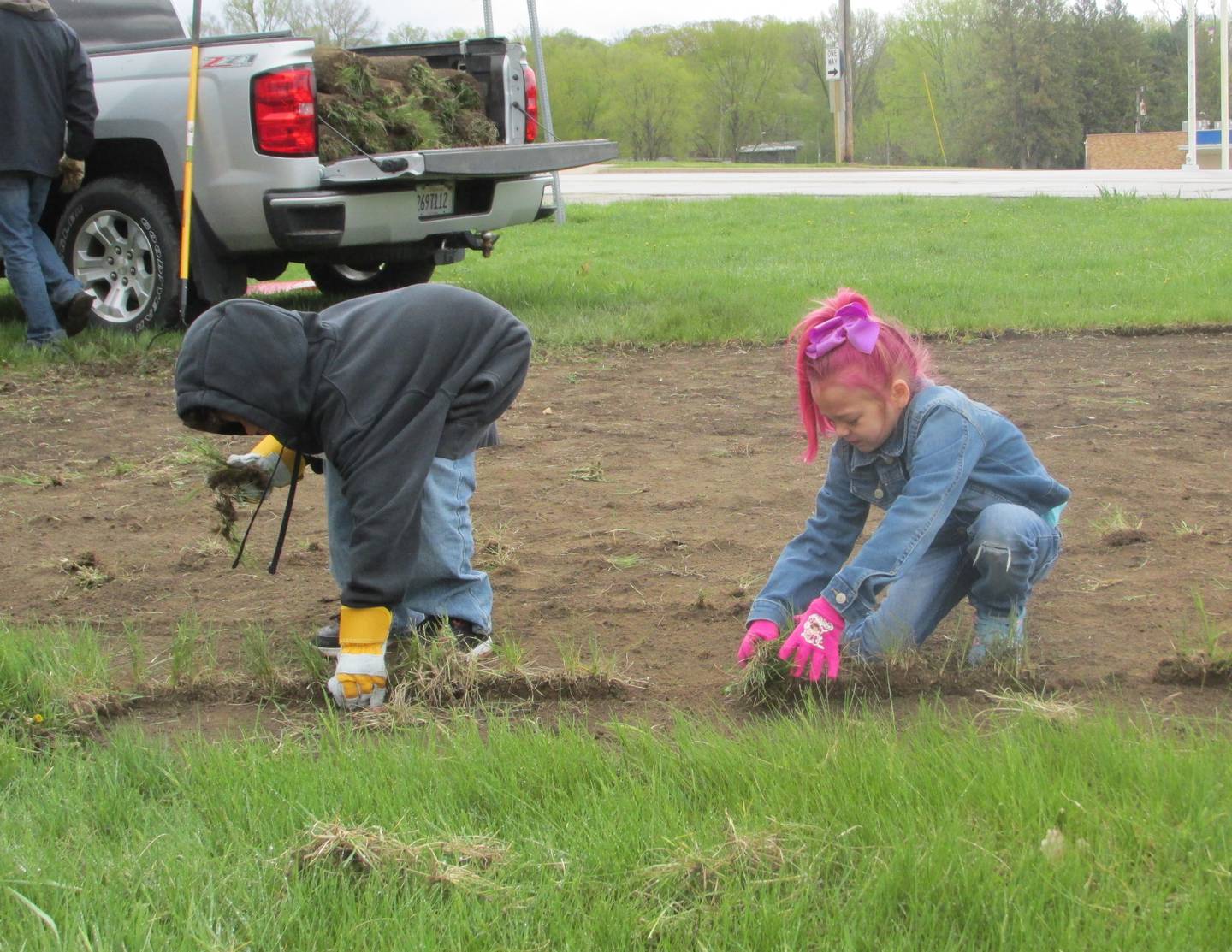 Kamari Johnson (left) and Karsyn Vaughn-Scott help gather sod Saturday, April 22, 2023, after it was cut to make way for a pollinator garden at the west entrance of Hopalong Cassidy Canoe Launch in Streator.