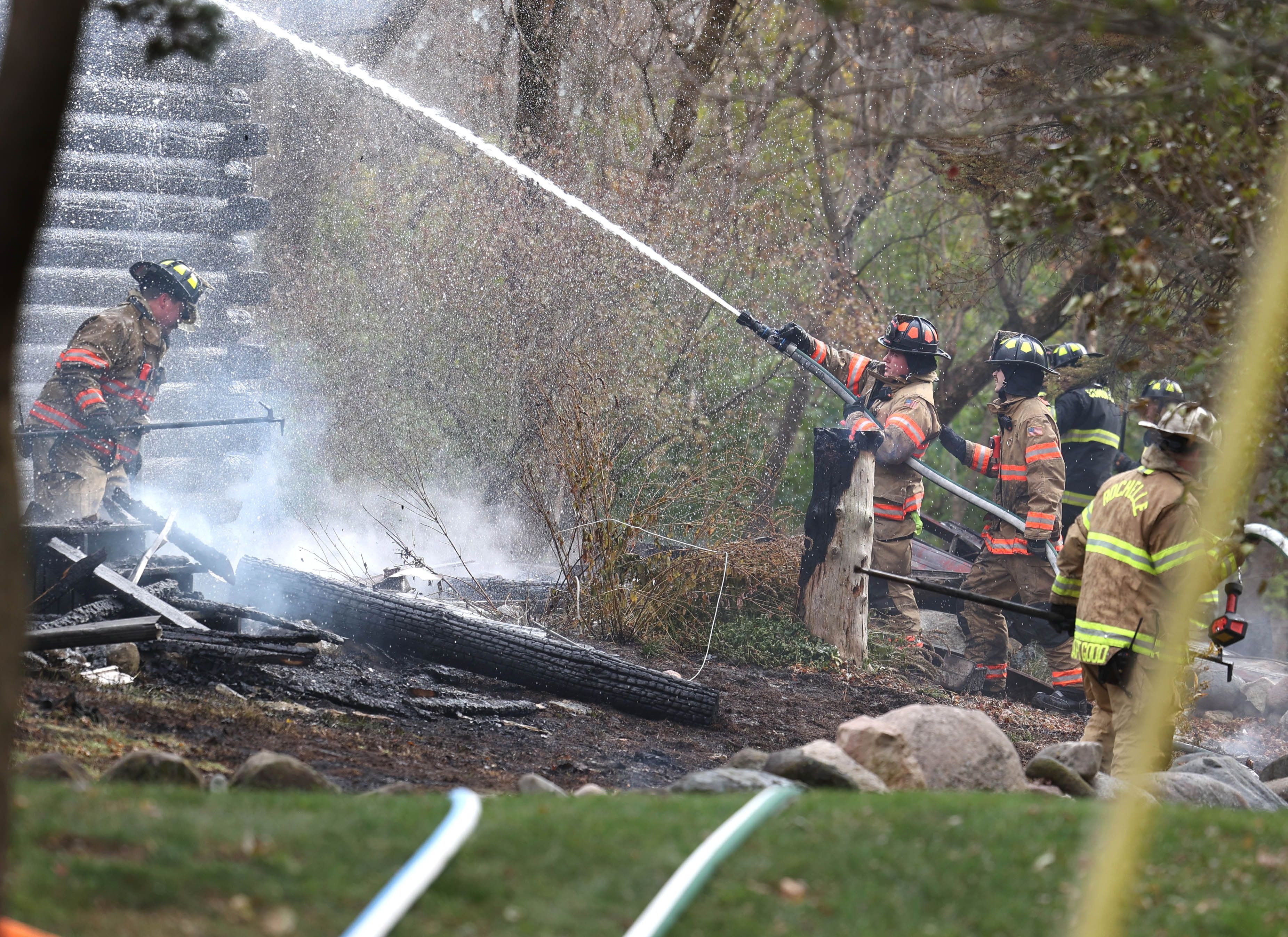 Firefighters put water on a smoldering house that was destroyed by fire Thursday, Nov. 13, 2025, near Shabbona Grove Road in Shabbona. Several local departments responded to the general alarm structure fire.