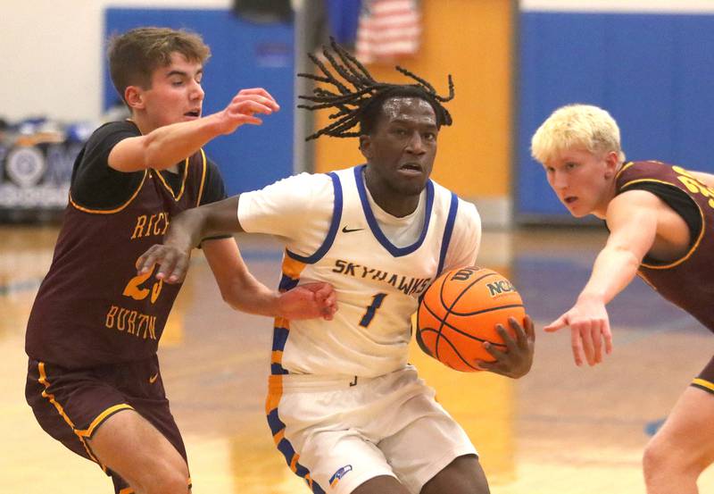 Johnsburg’s Jarrel Albea slips past Richmond-Burton’s William Gardner, left, and Luke Robinson, right, in varsity boys basketball onTuesday, Dec. 9, 2025, at Johnsburg High School in Johnsburg.