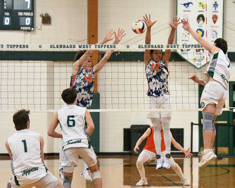 Oak Park River-Forest teammates Roann Doody, left, and Oak Park River Forest's Jimmie Chrusfield III (12) tries to block the spike of Glenbard West's Adam Graham (7) during the match up on Tuesday April 16, 2024, held at Glenbard West High School.