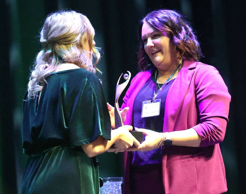Devyn Grzywa (right) is presented with the trophy after being announced as this year’s Athena Award recipient Thursday, Oct. 16, 2025, during the 35th annual Athena and Women of Accomplishment Award Reception at the Egyptian Theatre in DeKalb.winner of the 2025 Athena Award, Devyn Grzywa
