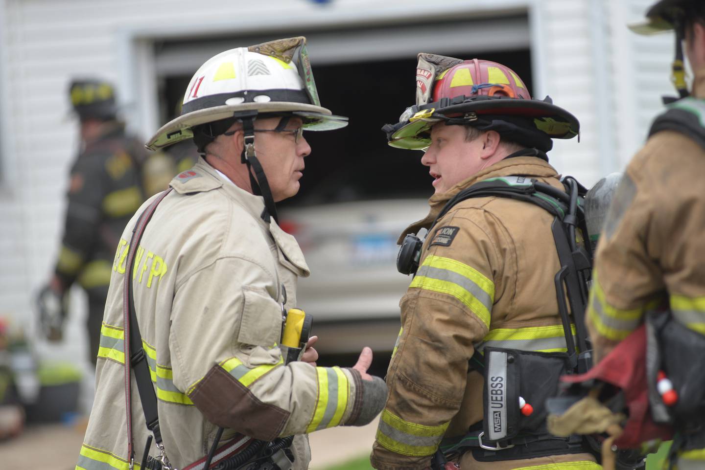 Oregon Fire Chief Michael Knoup (left) talks with one of the firefighters who responded to a fire in a home at 805 S. 8th St., in Oregon on Thursday, May 1, 2025.