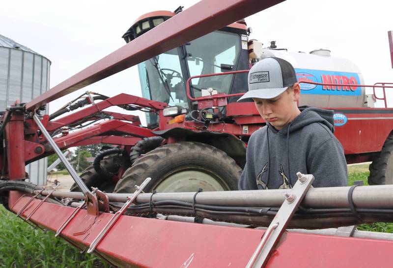 Eli Schweitzer, 12, changes the sprayer nozzles on a tractor Friday, June 16, 2023, on his dad, Mike Schweitzer’s farm in Malta.